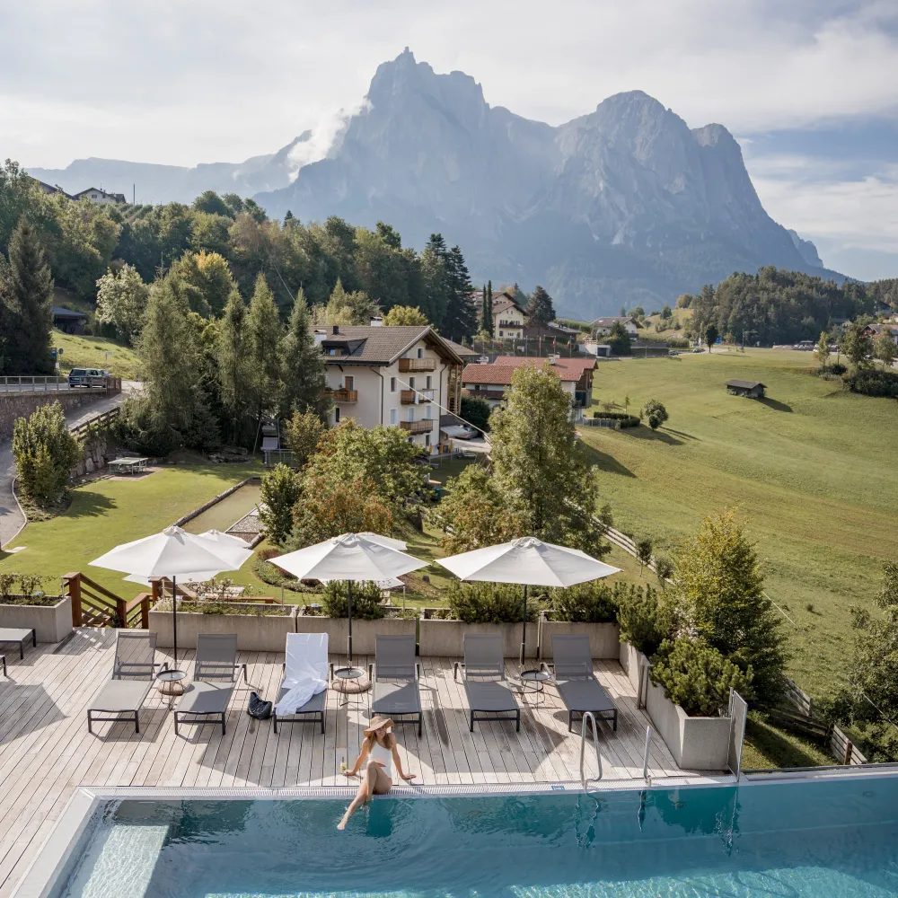 Outdoor-Pool mit Sonnenschirmen und Blick auf die Dolomiten am Alpenflora