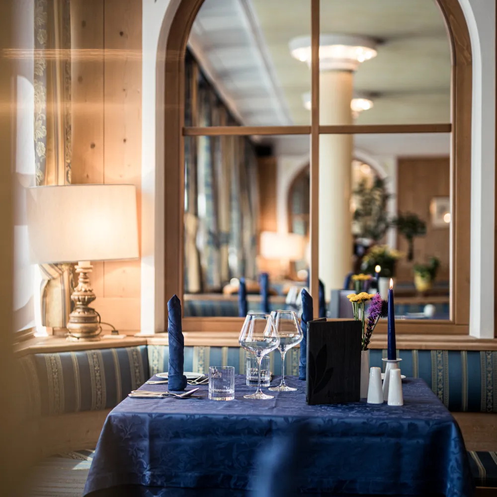 Festlich gedeckter Tisch im Restaurant des Wellnesshotels Alpenflora mit Weingläsern und Kerze.