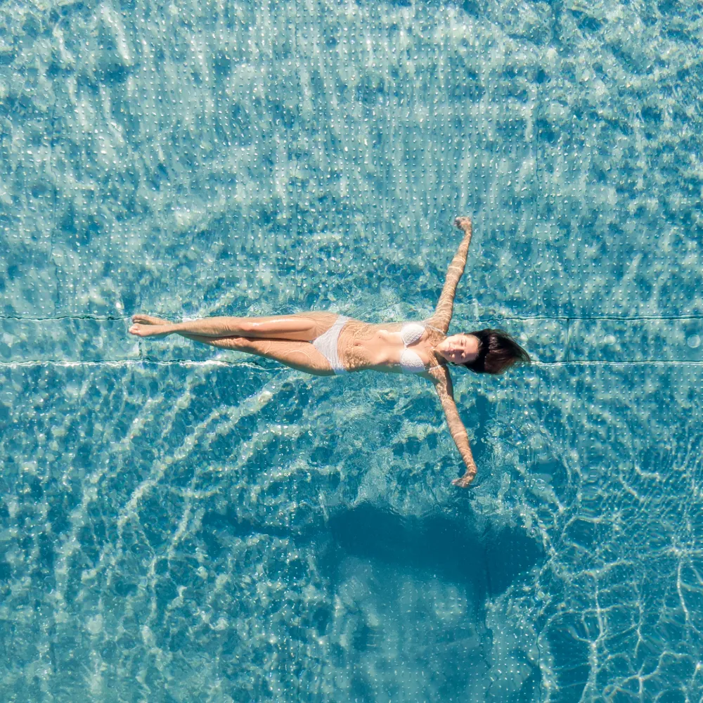 Donna che galleggia sulla schiena nella piscina turchese dell'Hotel Alpenflora