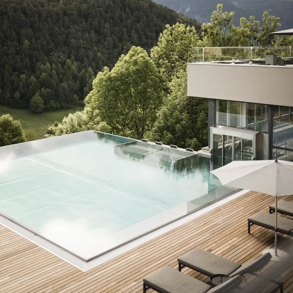 Infinity-Pool auf der Holzterrasse des Wellnesshotels Alpenflora mit Blick auf Wald und Berge
