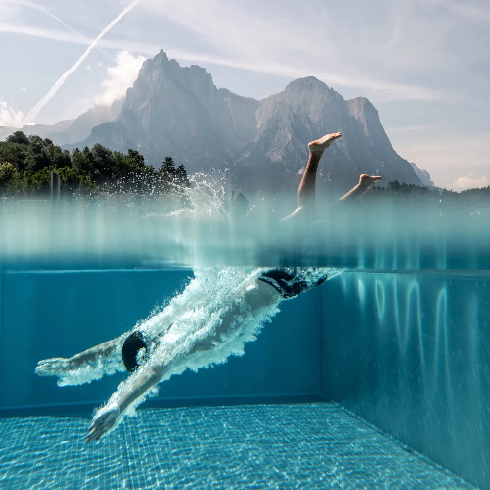Swimmer diving through the clear water of the pool at the Alpenflora