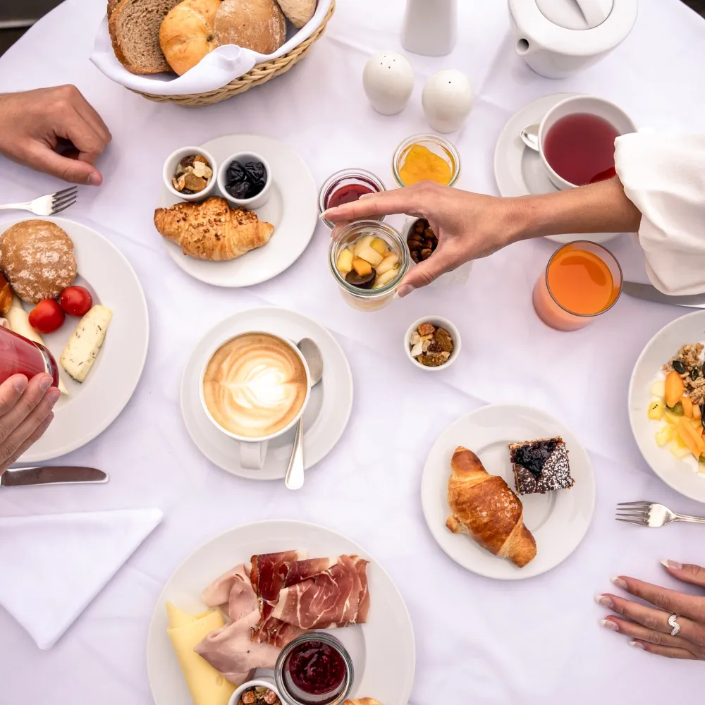 Reich gedeckter Frühstückstisch von oben mit Kaffee, Gebäck und Südtiroler Speck