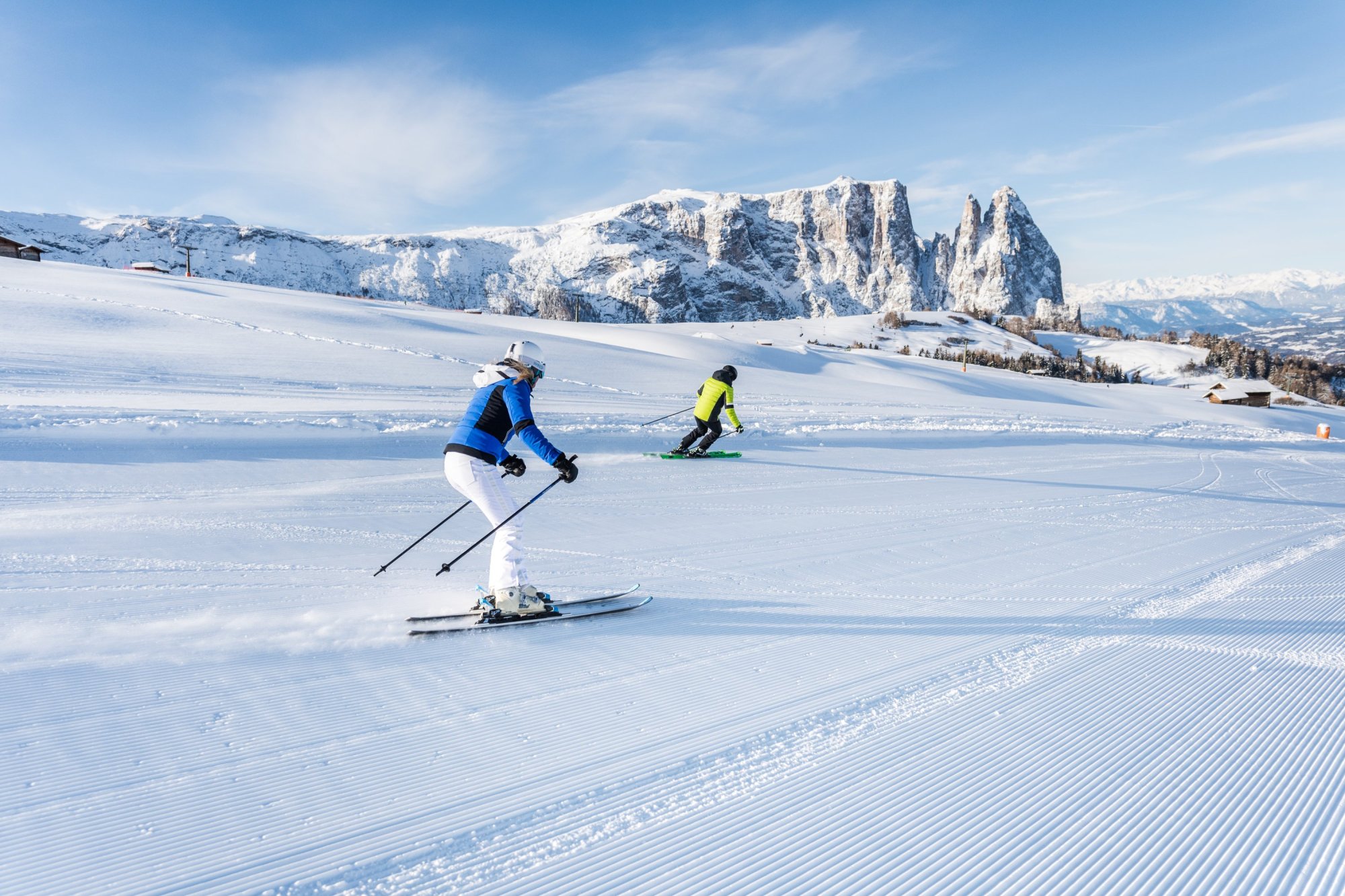 Zwei Skifahrer auf frisch präparierter Piste vor dem Bergpanorama der Dolomiten bei Kastelruth.