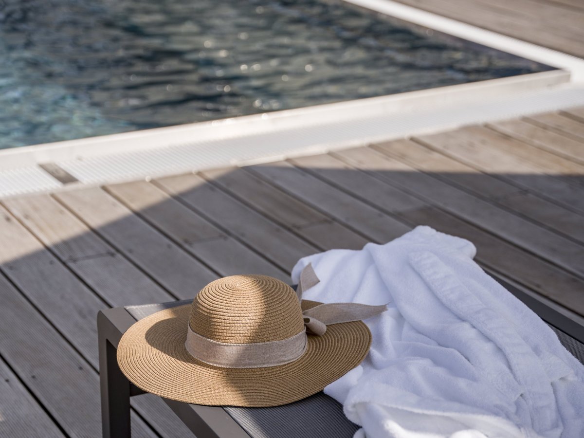 Cappello di paglia e accappatoio su un lettino a bordo piscina dell'Hotel Alpenflora a Castelrotto