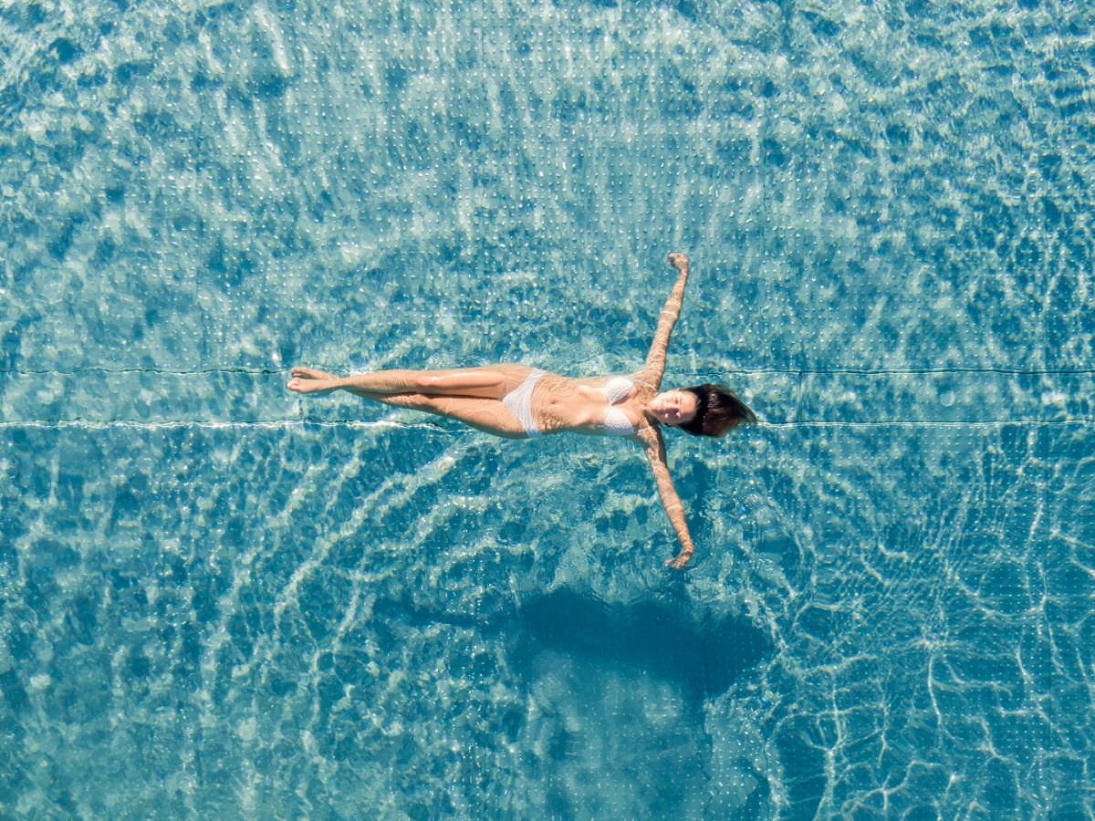 Donna che galleggia sulla schiena nella piscina turchese dell'Hotel Alpenflora
