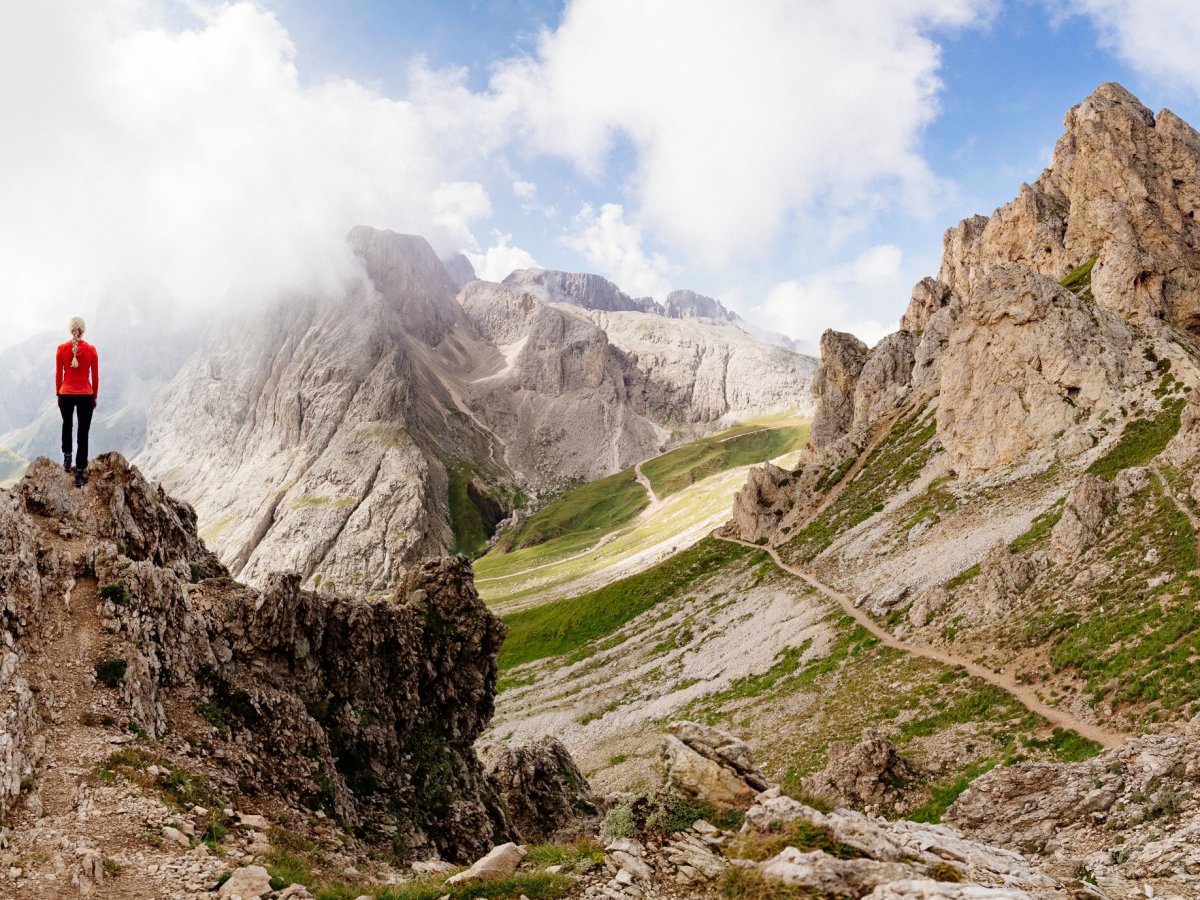Escursionista su una cresta rocciosa con ampia vista sulle Dolomiti vicino a Castelrotto