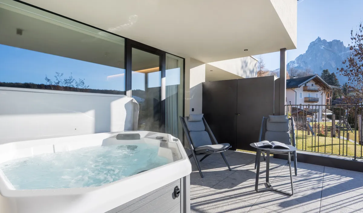 Privatterrasse mit Outdoor-Whirlpool, Liegestühlen und Blick auf die Berge im Wellnesshotel Alpenflora.