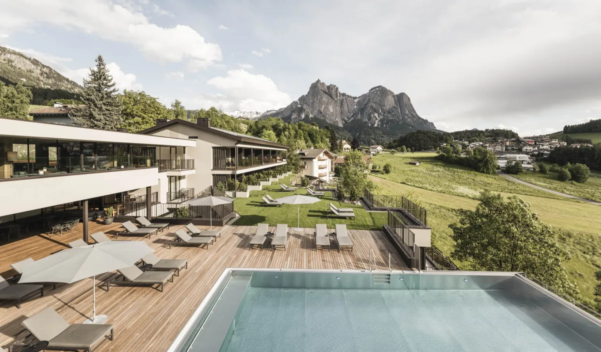 Außenansicht des Wellnesshotels Alpenflora mit Pool und Terrasse vor der Bergkulisse
