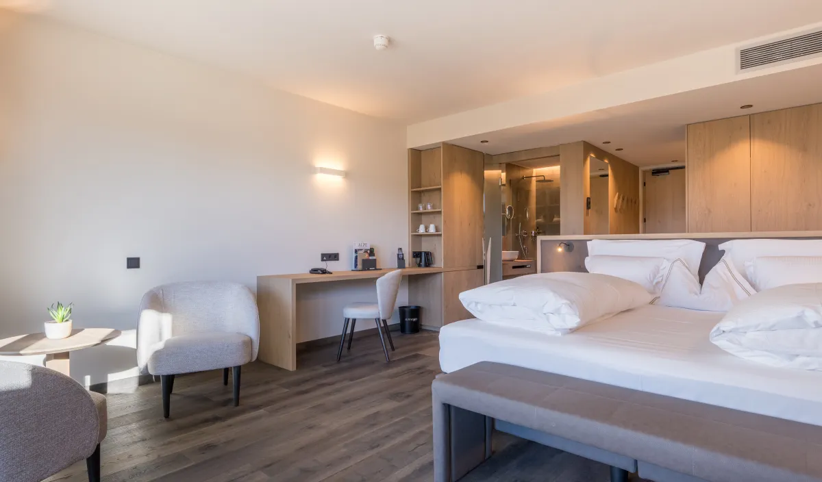 Doppelzimmer Garden Romantic im Wellnesshotel Alpenflora mit Doppelbett, Sitzecke und Schreibtisch in hellem, modernem Design.