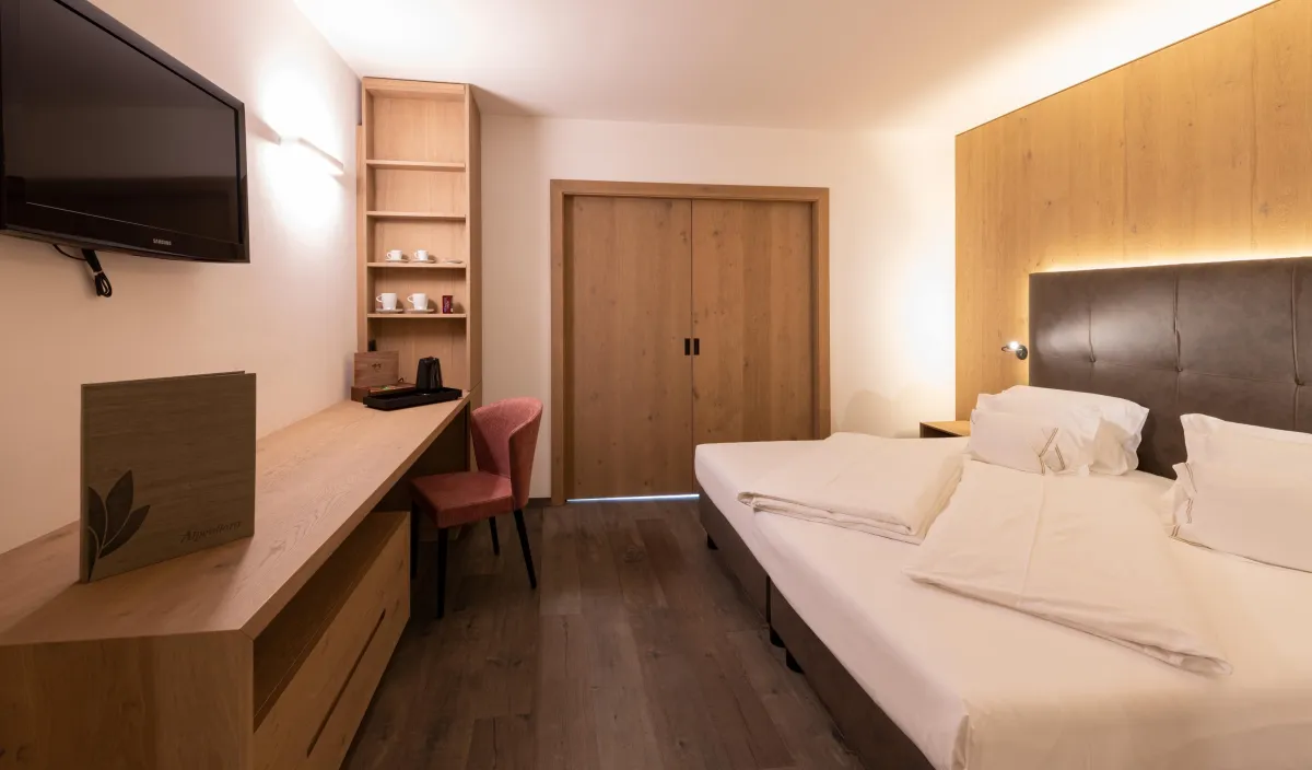 Camera da letto della Sun Suite con letto matrimoniale, scrivania, armadio in legno e sedia bordeaux.
