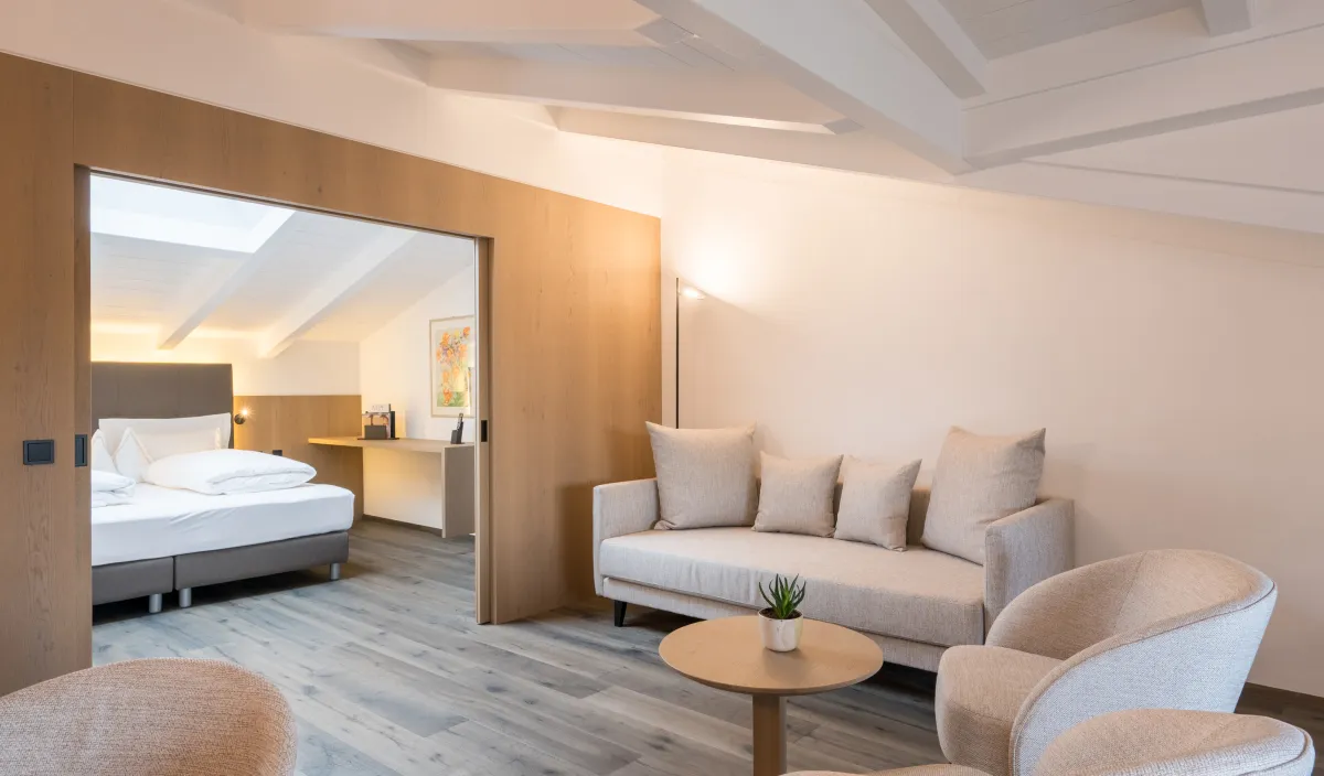 Zona giorno dell'Attico Suite con divano, poltrona, tavolino e passaggio alla camera da letto.