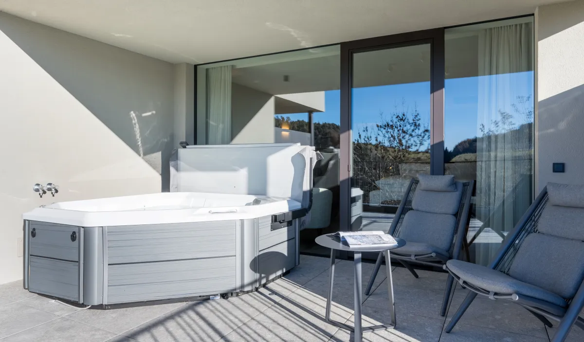 Überdachte Terrasse mit Whirlpool und zwei Liegestühlen im Doppelzimmer Garden Romantic.