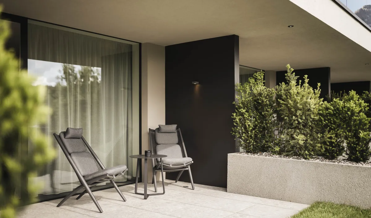 Private Terrasse mit zwei Liegestühlen, Beistelltisch und Bepflanzung vor der Zimmerfassade.