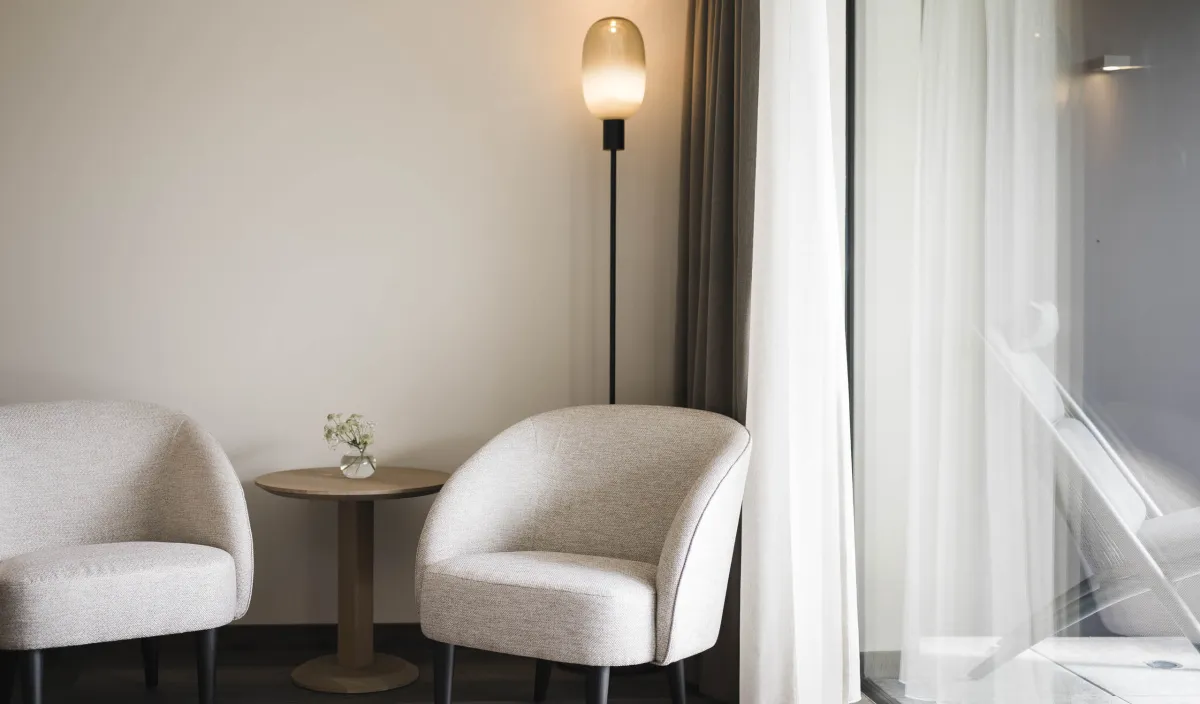 Gemütliche Sitzecke im Zimmer Garden Relax mit zwei Polstersesseln, Beistelltisch und Stehleuchte.