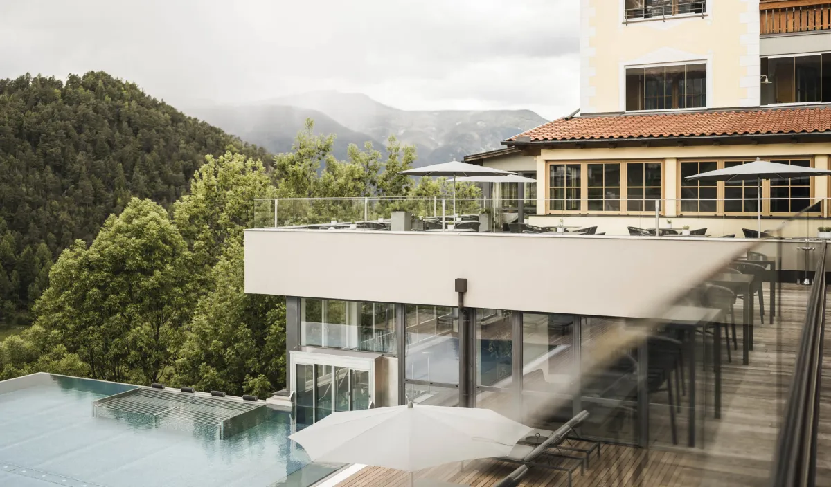 Das Wellnesshotel Alpenflora in Kastelruth mit Infinity-Pool, Sonnenterrasse und Blick auf die Dolomiten