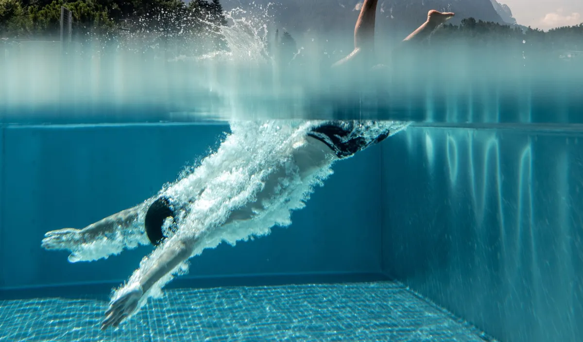 Schwimmer taucht ins klare Wasser des Pools im Wellnesshotel Alpenflora