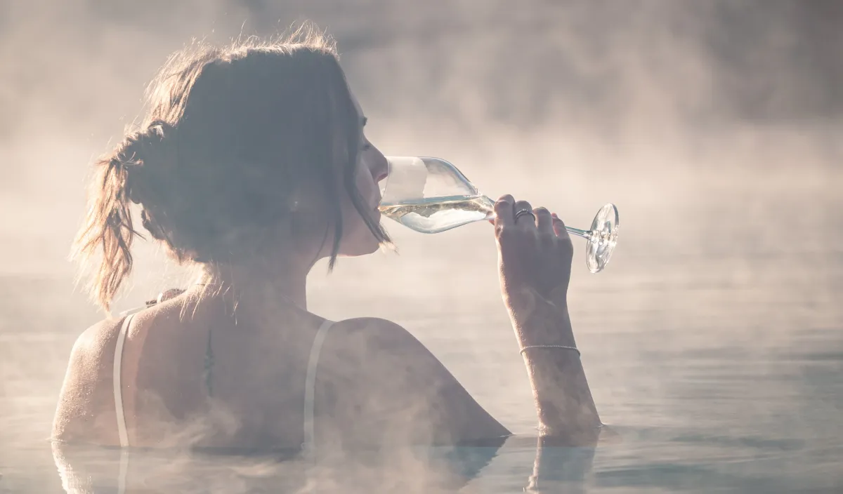Woman enjoying a glass of white wine in the steaming warm water at the Alpenflora