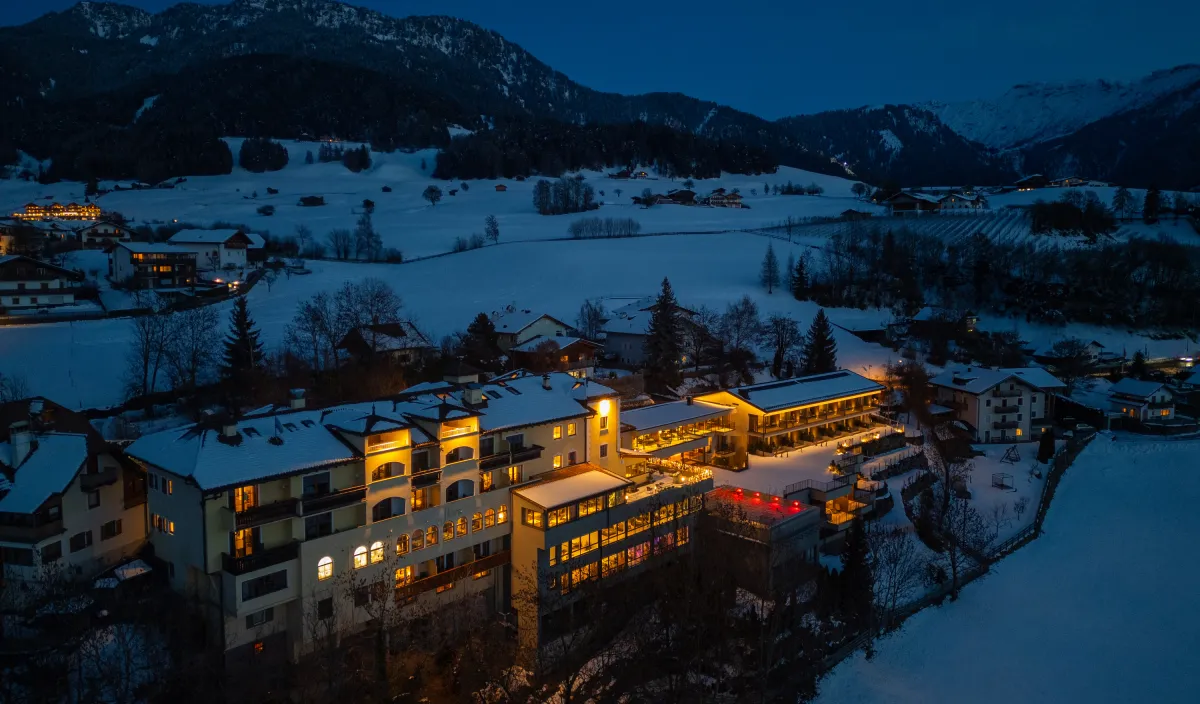 Wellnesshotel Alpenflora in der winterlichen Abenddämmerung mit beleuchteter Terrasse