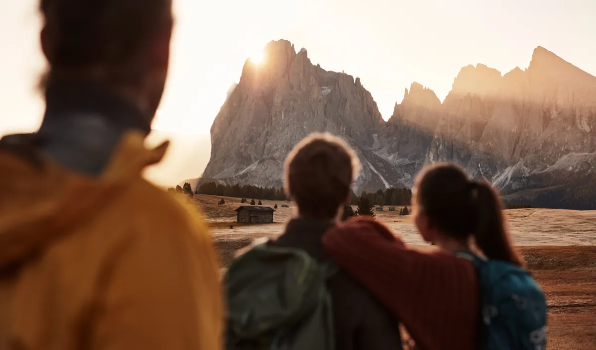 Three hikers looking at the Dolomites at sunset near Castelrotto