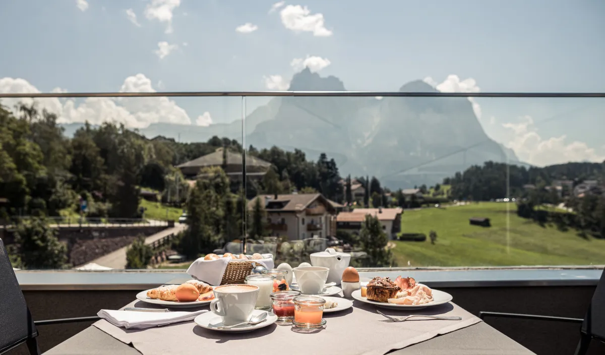 Laid breakfast table on the sun terrace of the Alpenflora with a view of the mountains
