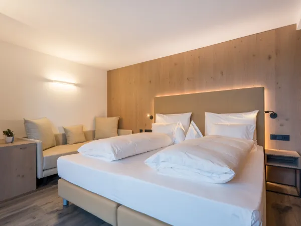Doppelbett mit gepolstertem Kopfteil, Holzwandverkleidung und Tagesbett mit Kissen im Zimmer Panorama Superior.