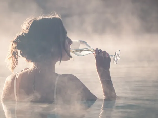 Woman enjoying a glass of wine in the steaming warm water at the Alpenflora