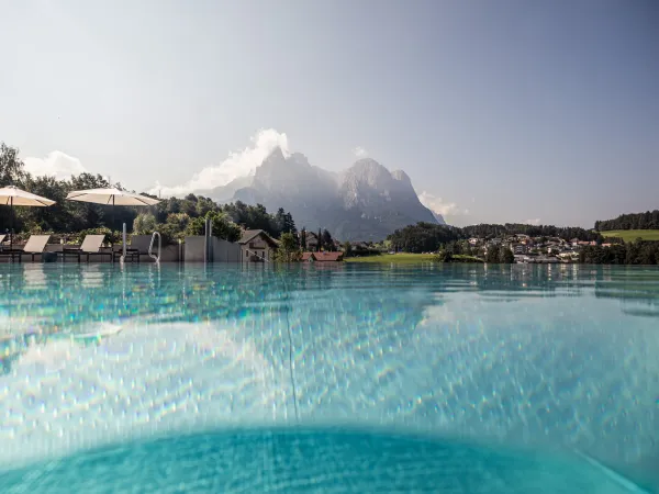 Infinity pool at the Alpenflora with parasols and a view of the Dolomites