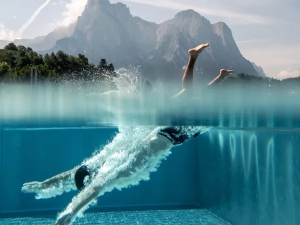 Swimmer diving in the Alpenflora pool against the backdrop of the Dolomites