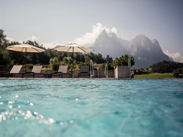 Outdoor-Pool mit Sonnenschirmen und Blick auf die Dolomiten am Alpenflora