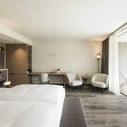 Doppelzimmer Garden Relax mit Doppelbett, Schreibtisch, zwei Sesseln und offenem Zugang zur Terrasse.