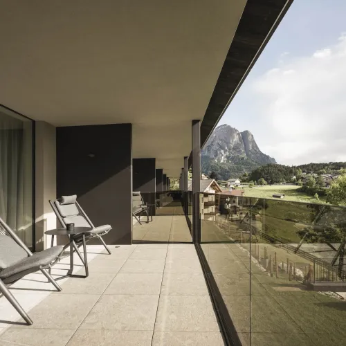 Terrace of the Garden View double room with lounge chairs, glass balustrade and views of the Schlern.