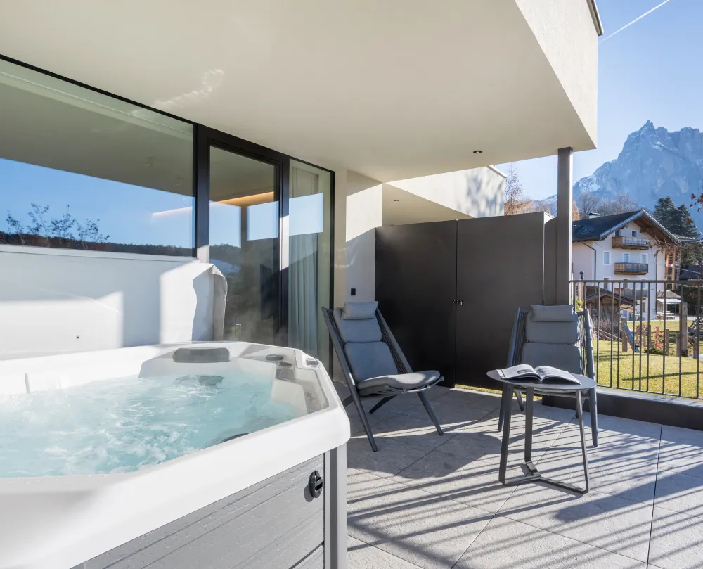 Privatterrasse mit Outdoor-Whirlpool, Liegestühlen und Blick auf die Berge im Wellnesshotel Alpenflora.