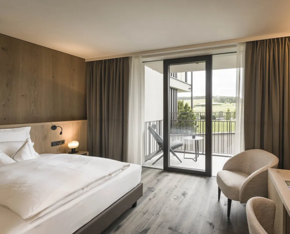 Einzelzimmer Garden Single Stay im Wellnesshotel Alpenflora mit Bett, Sessel, Schreibtisch und Balkon mit Blick ins Grüne.